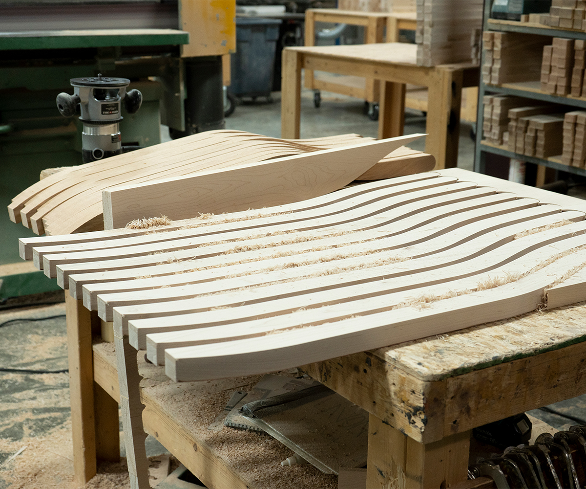 Curved hardwood chair slats laid out on a workbench in an Amish workshop.