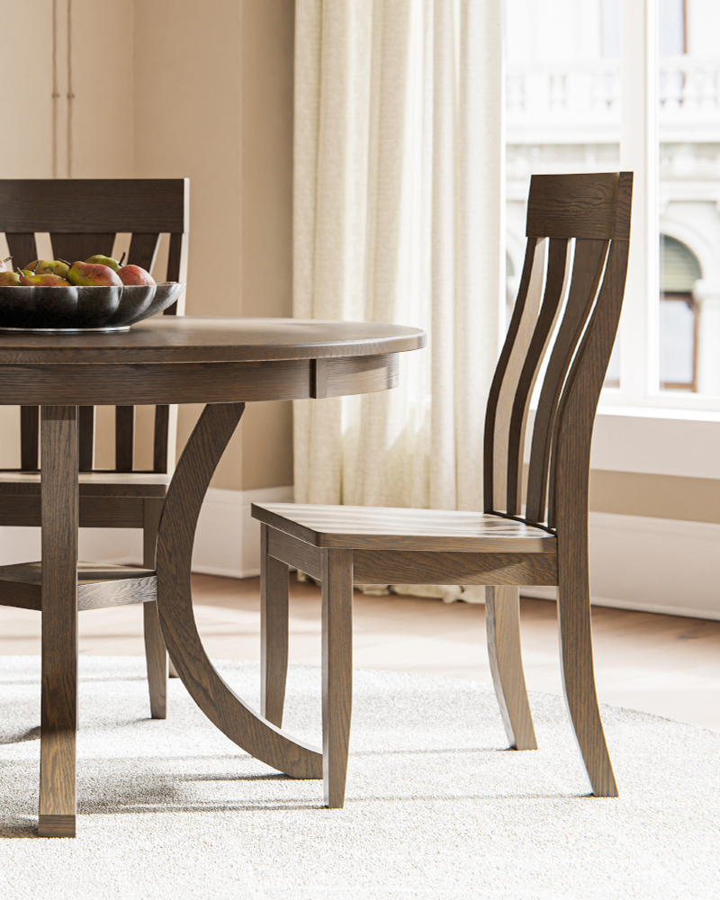 Solid wood round dining table with matching slat back chairs in bright dining room